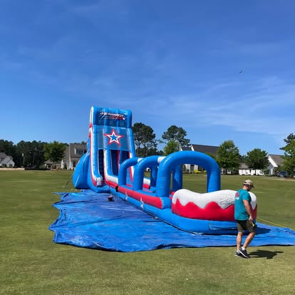 A large patriotic slip-and-slide inflatable on a neighborhood field